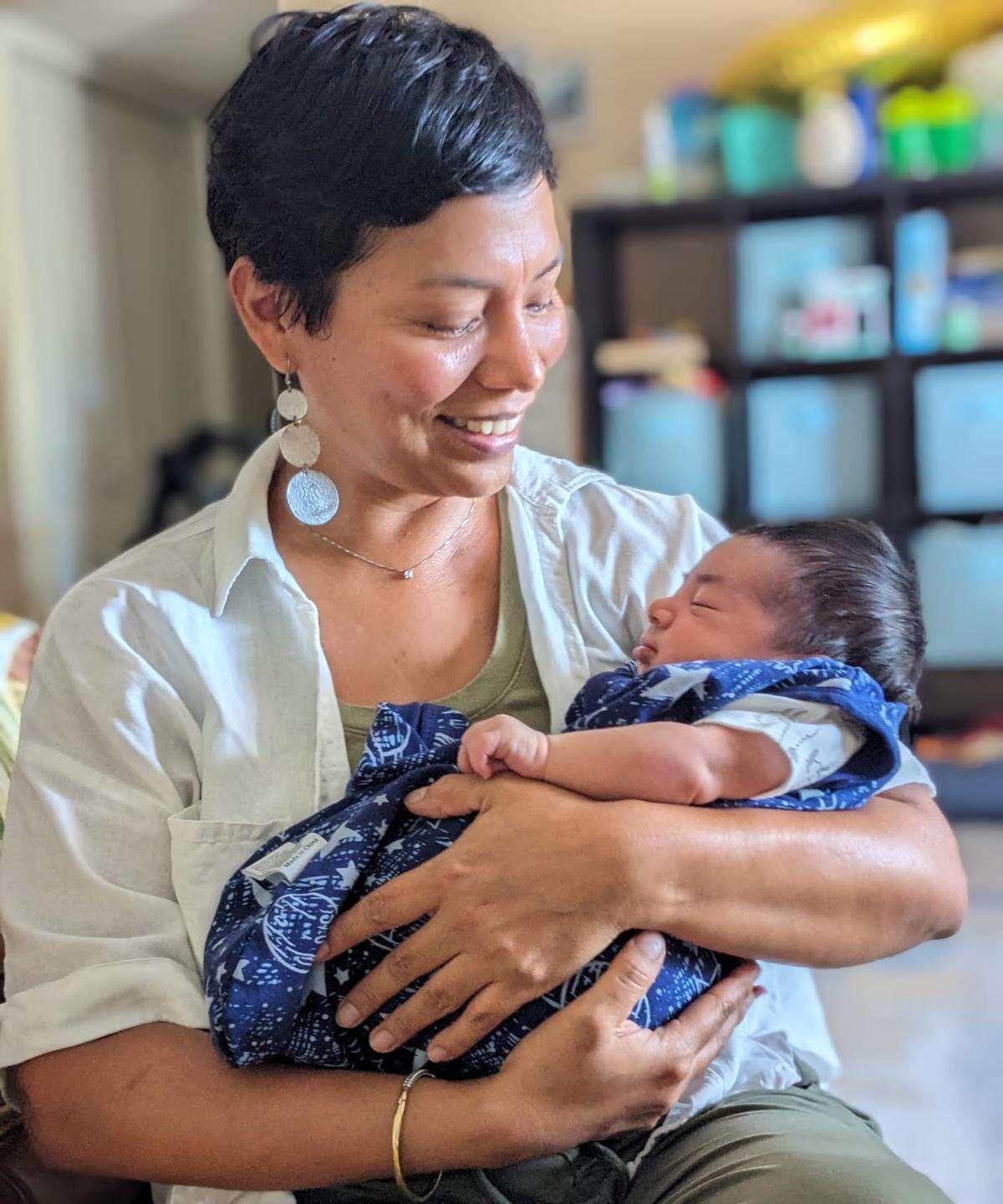 Elia looking down at a newborn in her arms